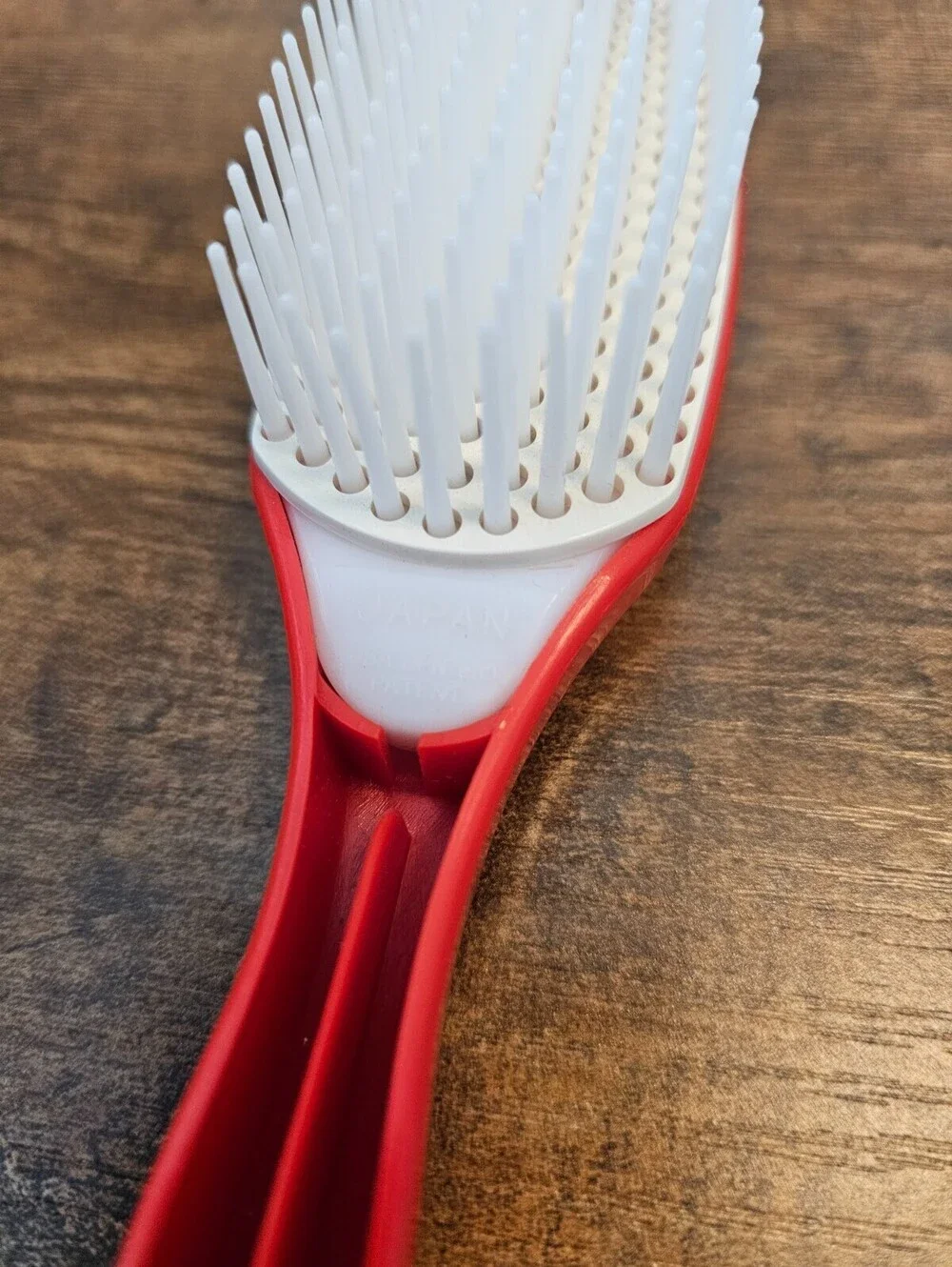 Vintage 1970s hair brush with a red handle and flexible white bristles